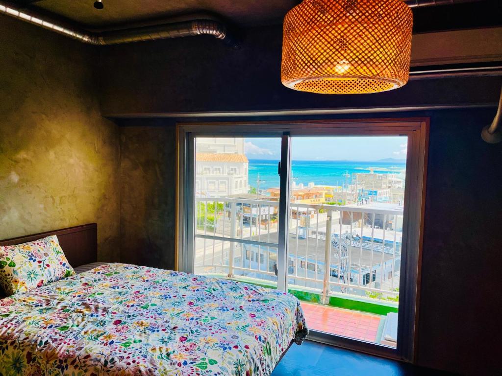 a bedroom with a bed and a large window at シートピア恩納村Ocean 贅沢快適なデザイナーズ空間と蒼い海 in Onna