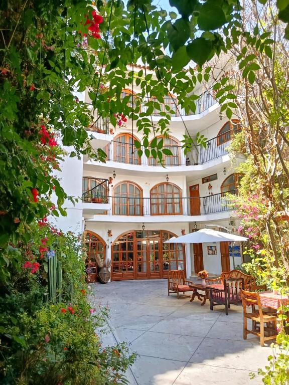 阿亚库乔Casa Munayki的一座白色的大建筑,前面设有桌椅