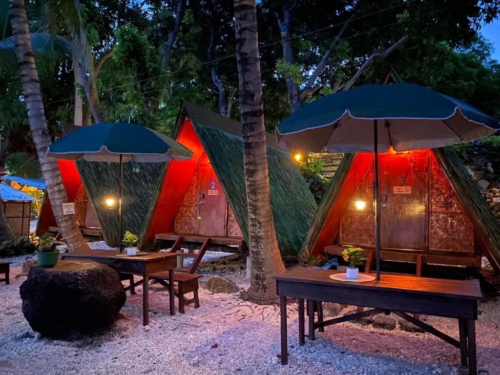 un grupo de tiendas de campaña con mesas y sombrillas en Alfonsa Tent Ground - Camp By The Sea, en Oslob