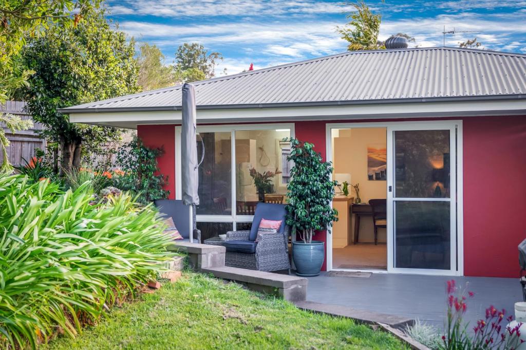 a red house with a porch and a chair at Milton Village Retreat - secluded comfort in Milton