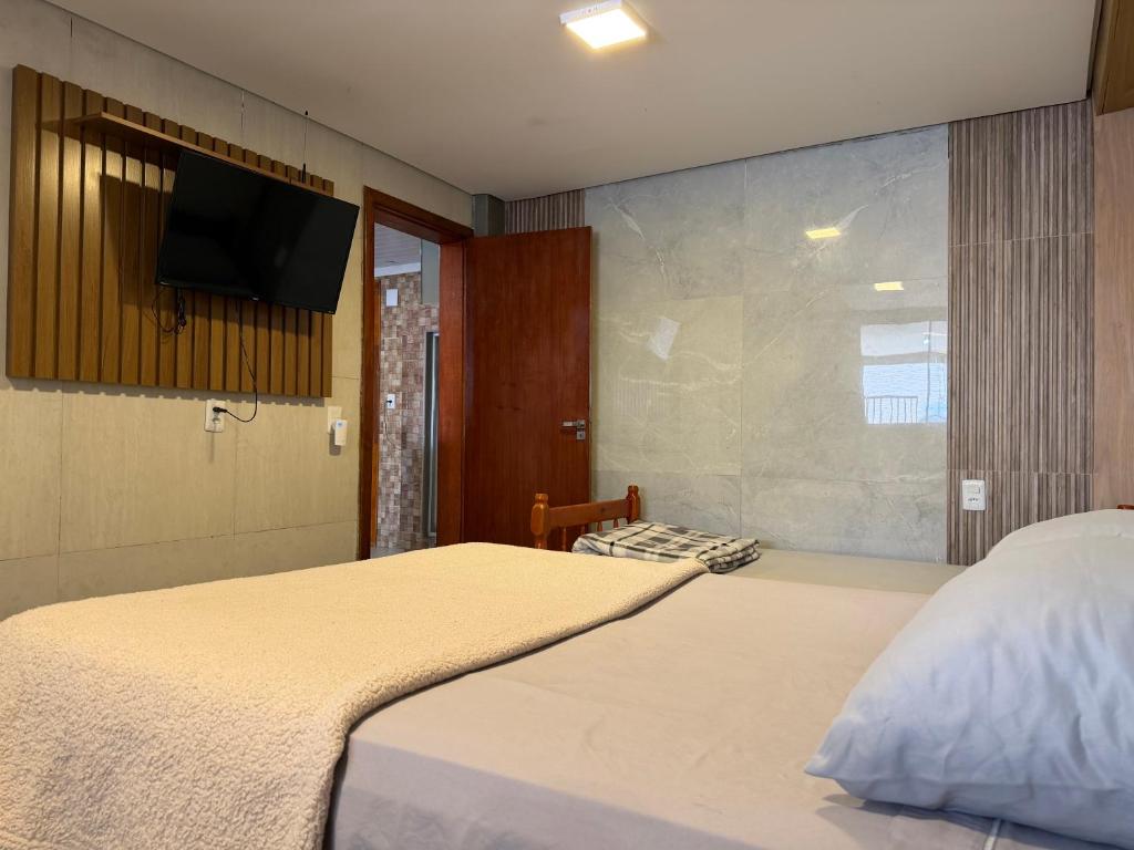 a bedroom with a bed with a tv on the wall at Moradas Desterro, próximo ao aeroporto 01 in Florianópolis