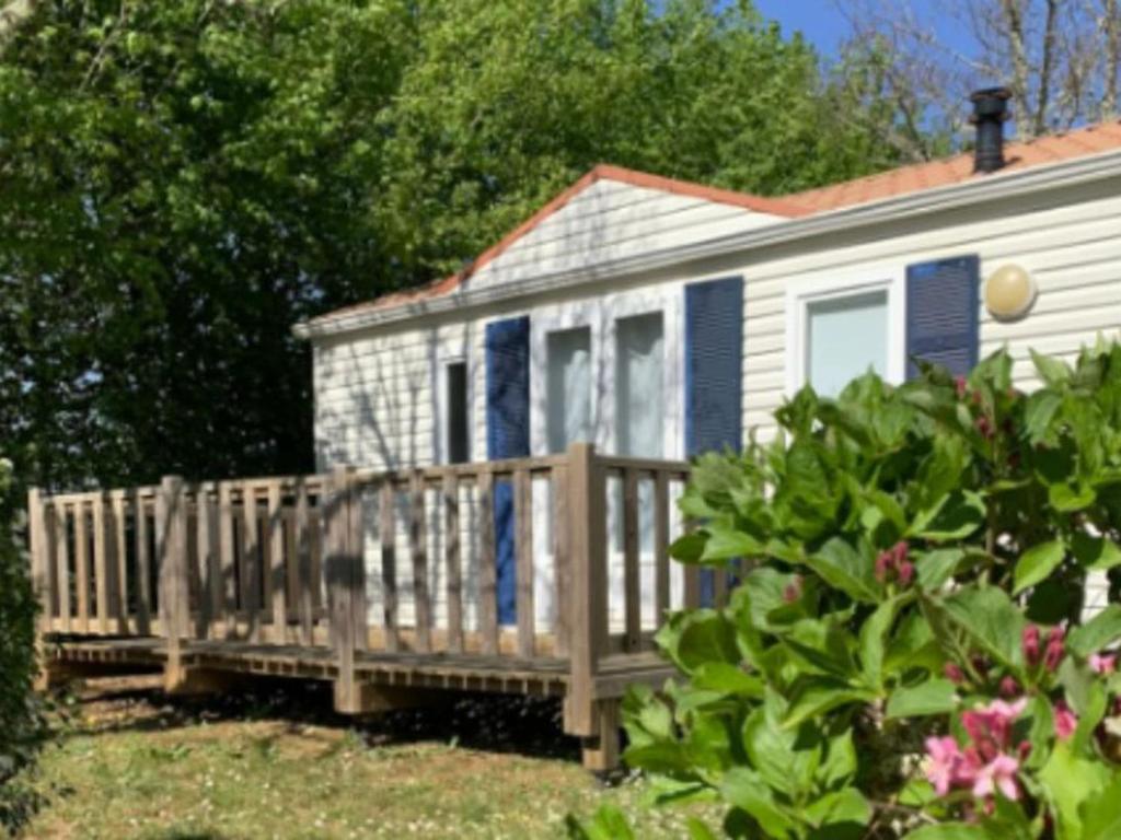 une petite maison blanche avec un porche en bois dans l'établissement Mobil Home 27m² avec Terrasse à Limeuil - 5 personnes - API-1-52-837, à Paunat