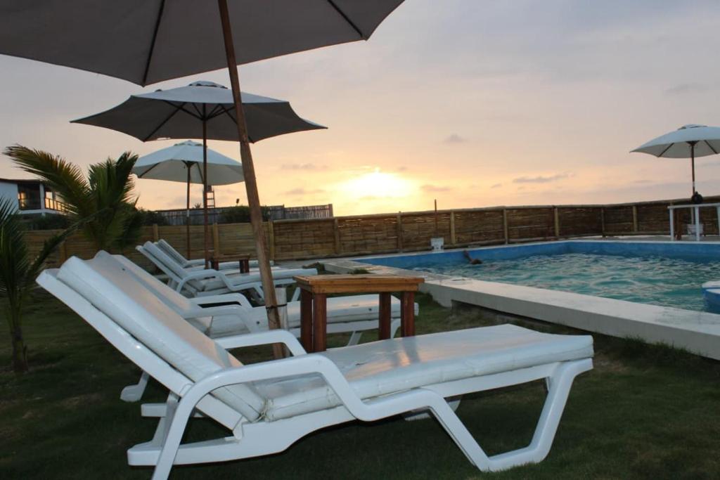 a group of chairs and umbrellas next to a swimming pool at Kala Hotel in Bocapán