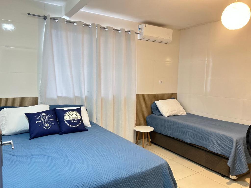 帕罗卡Ocean Residence - Aptos Pé na Areia Ponta do Papagaio的有两张床和一扇窗户的酒店房间