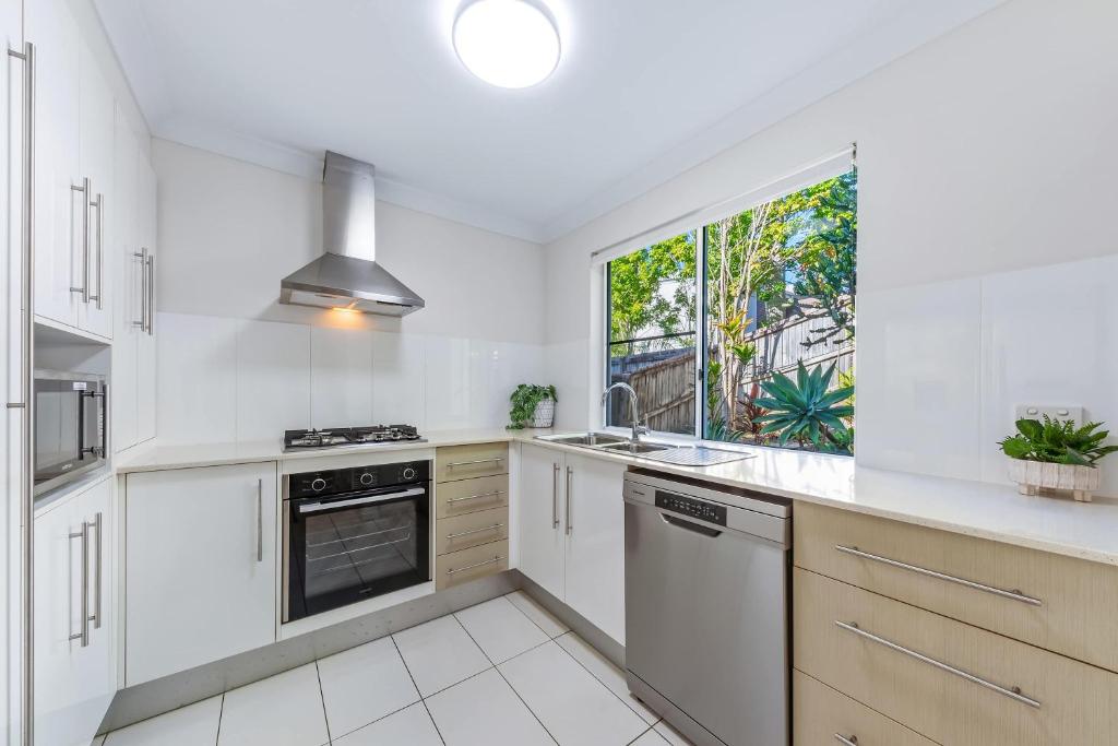 a kitchen with white cabinets and a window at Tropical Resort Apartment in Cannonvale