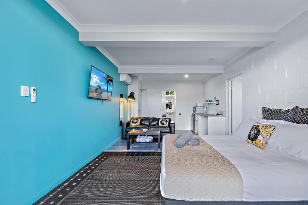 a bedroom with a white bed and a blue wall at Airlie Sun & Sand Accommodation #2 KIDS STAY FREE in Airlie Beach