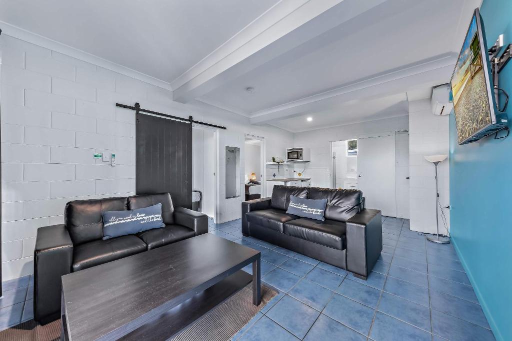 a living room with two leather couches and a table at Airlie Sun & Sand Accommodation #3 KIDS STAY FREE in Airlie Beach