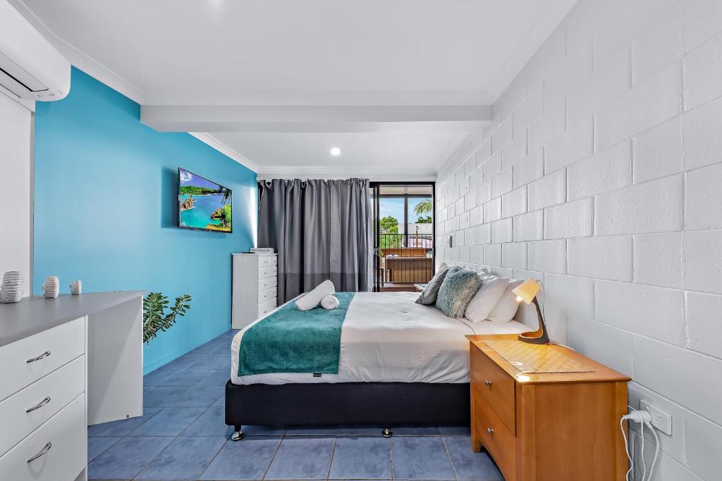a bedroom with a bed and a blue wall at Airlie Sun & Sand Accommodation Studio #1 KIDS STAY FREE in Airlie Beach