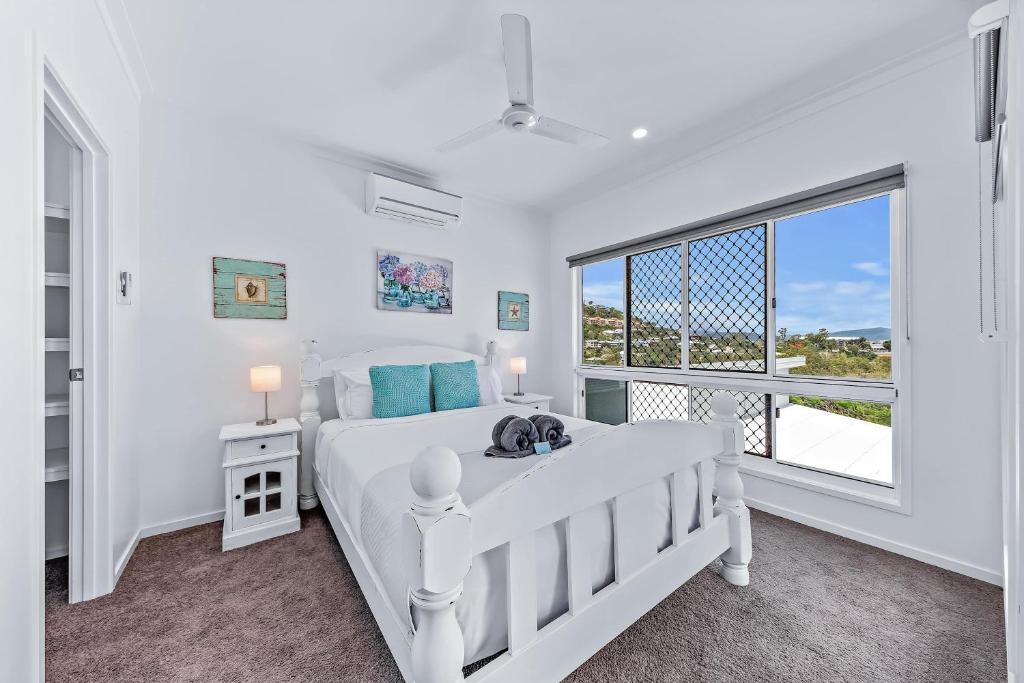 una camera bianca con un letto e una grande finestra di Seascape Whitsundays ad Airlie Beach