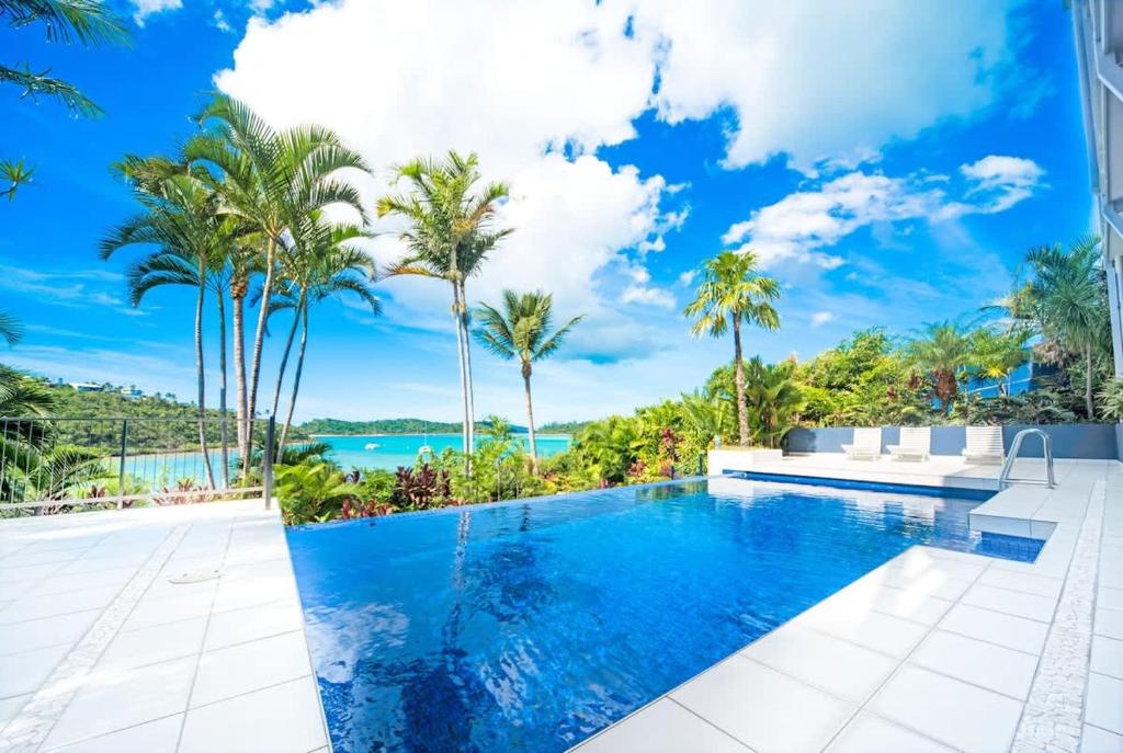 einen Pool in einer Villa mit Palmen in der Unterkunft Baybliss Escape #1 - Adults Only in Shute Harbour