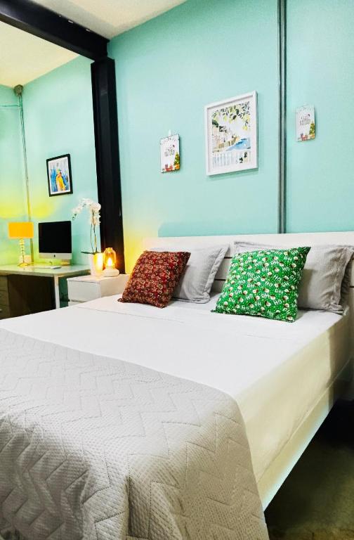 a bedroom with a white bed with colorful pillows at Loft ejecutivo con Aire Acondicionado, cerca de Clinica Duarte y UFPS in Cúcuta