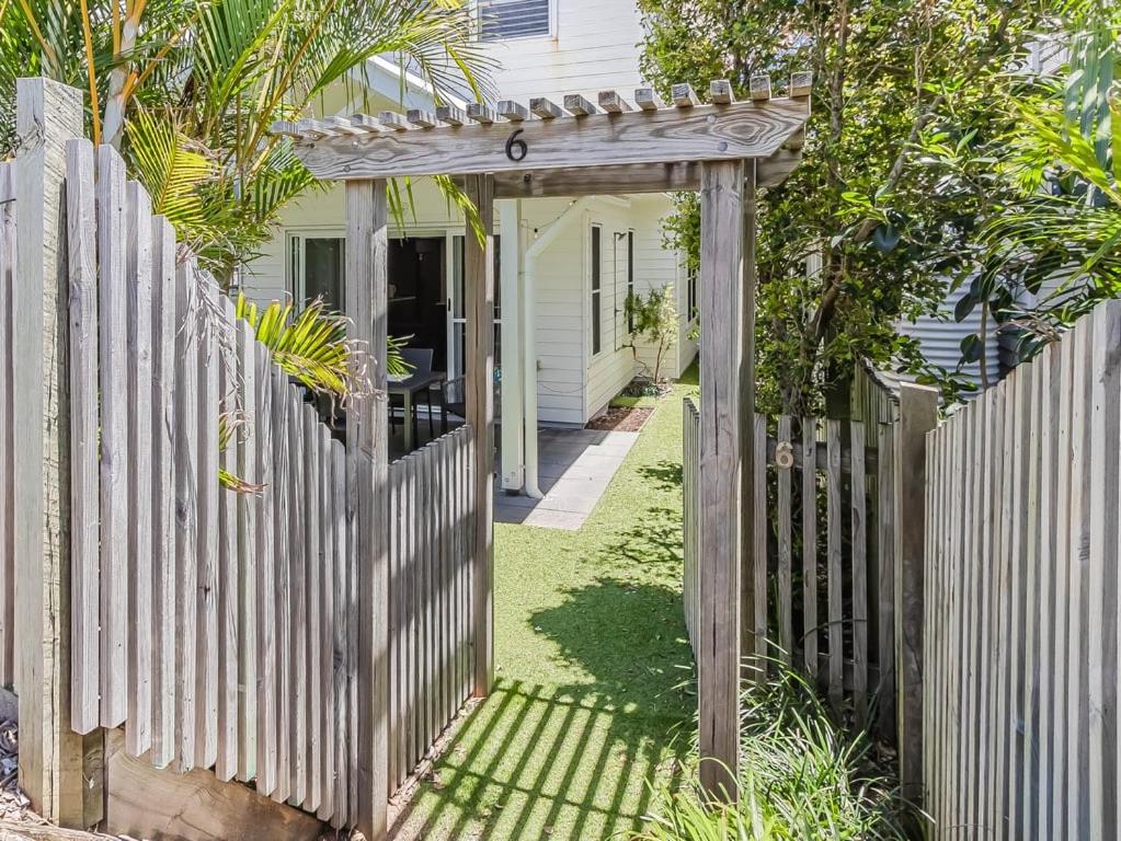 un cancello in legno di fronte a una recinzione bianca di Dianella Dunes a Casuarina