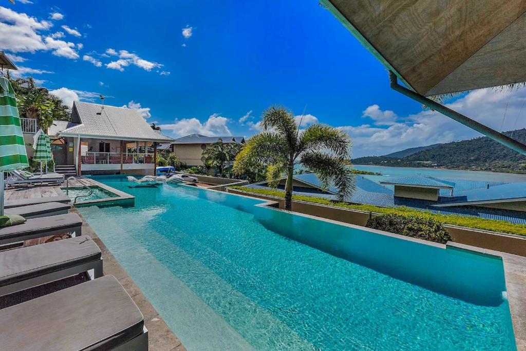 a swimming pool with a view of a house at Amalfi Whitsunday Retreat Infinity Pool SeaViews in Airlie Beach