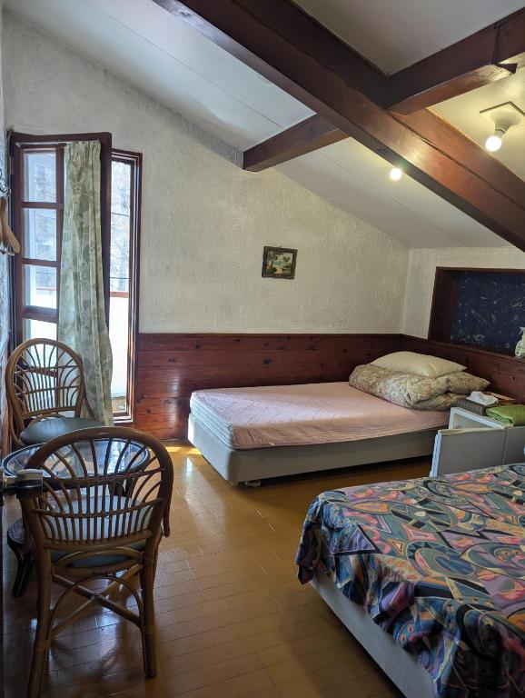 a bedroom with two beds and a table and chairs at Hachiko Inn in Myoko