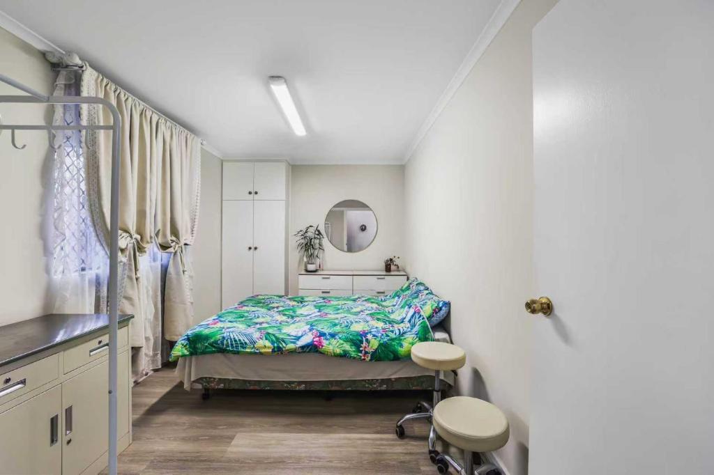 ein Schlafzimmer mit einem Bett und zwei Hockern in der Unterkunft Unley rd parkside Adelaide in Unley