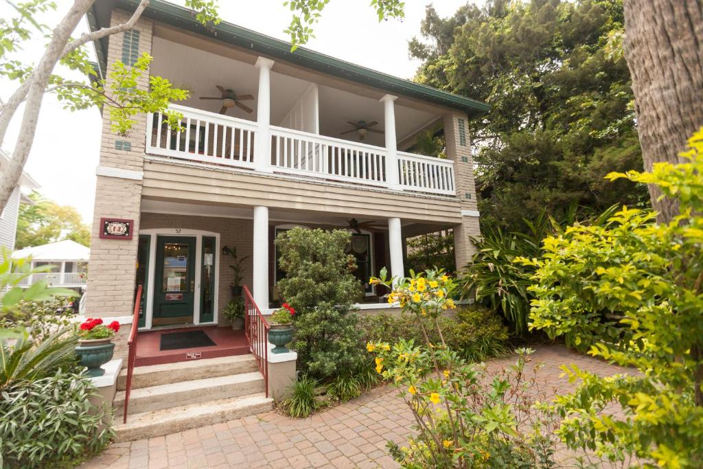 an old house with a porch and flowers in the yard at Inn on Charlotte Boutique Hotel in Saint Augustine