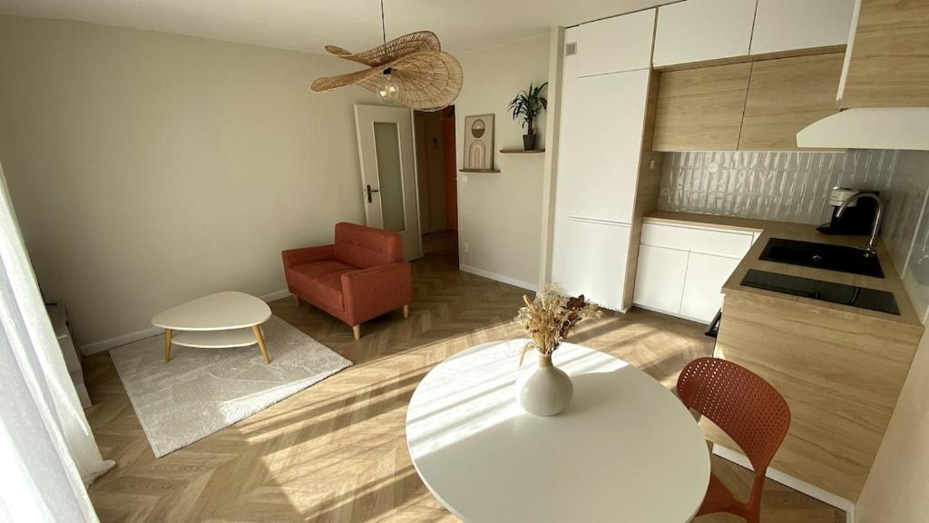 a living room with a white table and a red chair at Charming 2-room apartment, Grand Annecy in Meythet