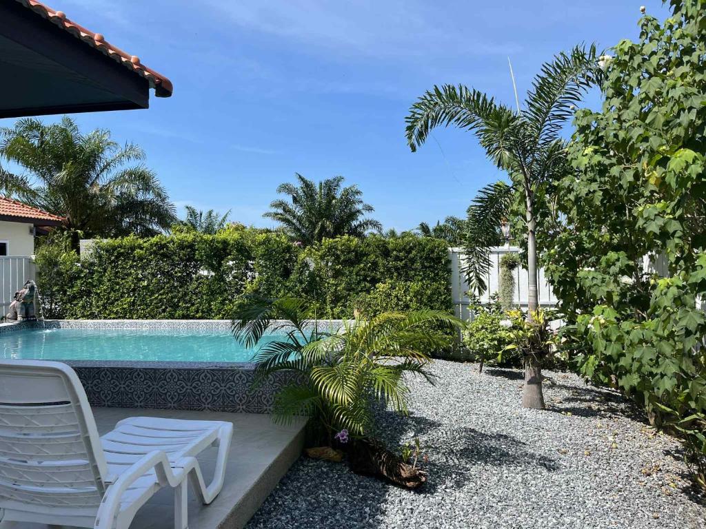 a backyard with a swimming pool and two chairs and a palm tree at Villa Cattleya by orchids pool villas in Ko Lanta