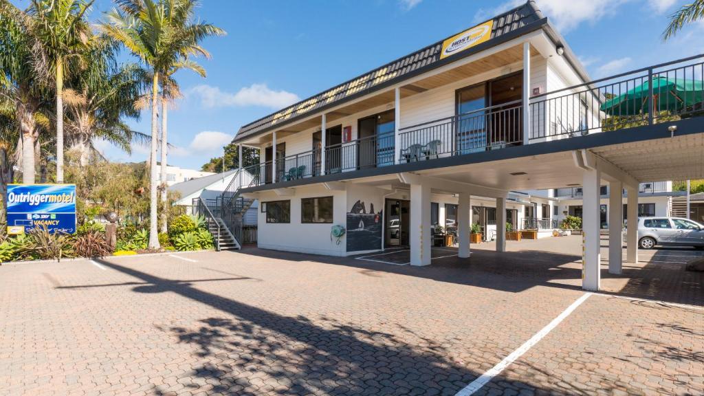 a building with a balcony and a parking lot at Outrigger Motel in Paihia