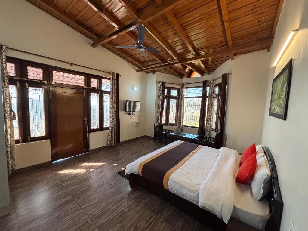 a bedroom with a large bed in a room with windows at Hotel Goludev Valley View in Nainital