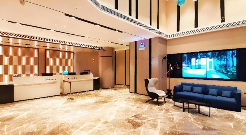 a lobby with a couch and a large screen television at Echarm Hotel Wuhan Gaotie Jianshe 2nd Road Metro Exit in Wuhan