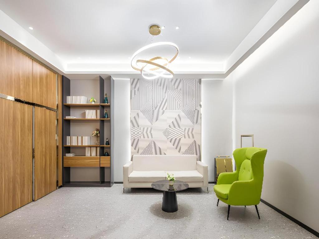 Una sala de estar con una silla verde y un sofá. en Borrman Hotel Suzhou Wujiang Zhongshan North Road Pedestrian Street, en Suzhou