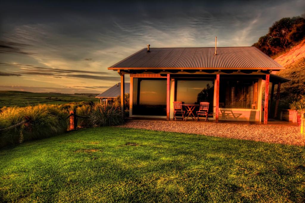 a house with a table and chairs in the grass at Anchors Port Campbell in Port Campbell