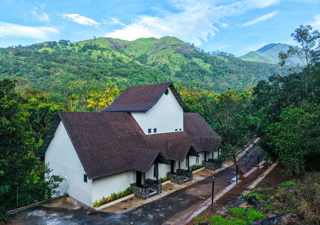 an overhead view of a house with mountains in the background at Achutham Cottages Wayanad by VOYE HOMES - Nature Luxe near Banasura Dam in Padinjarathara