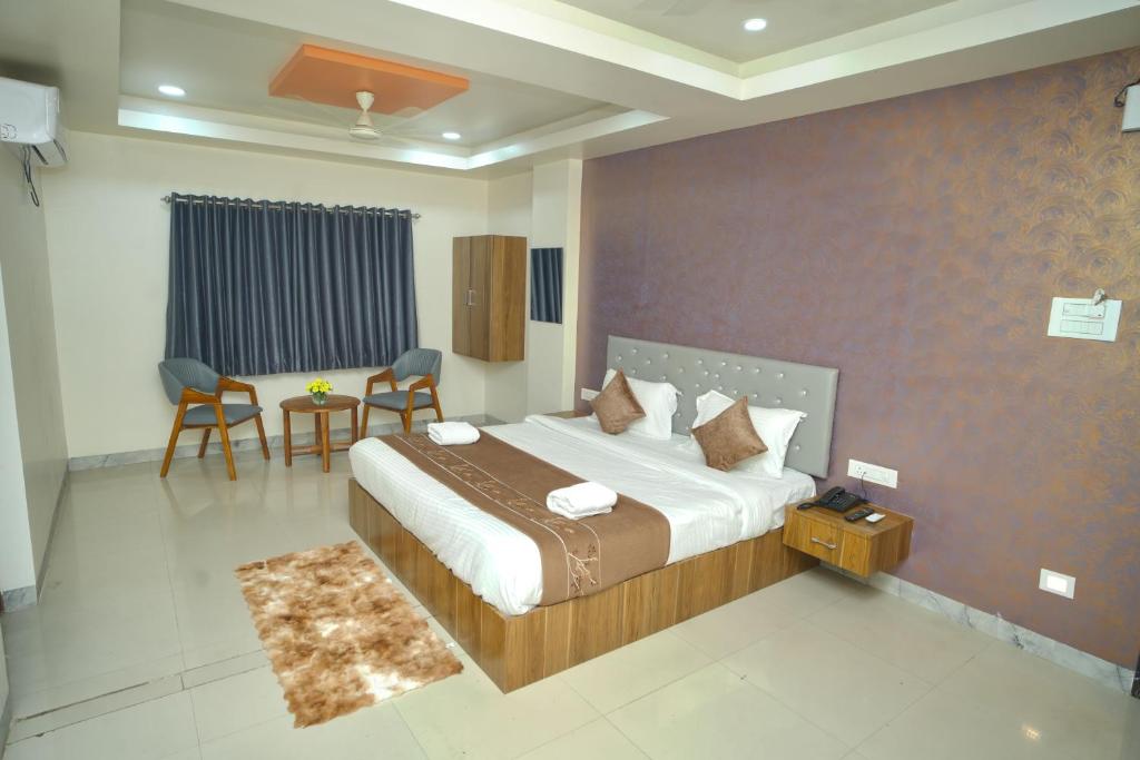 AurangabadにあるHotel Mauli executive & Restaurantのベッドとテーブルと椅子のある寝室