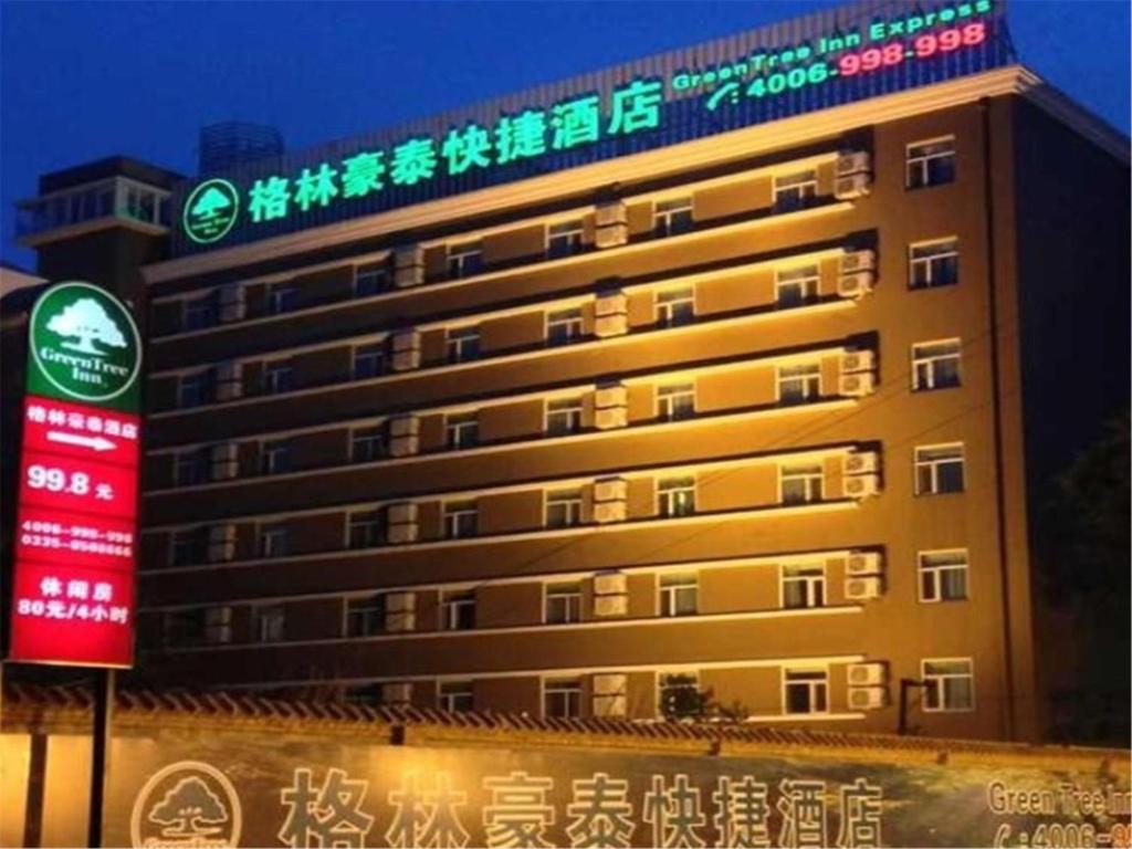 un edificio con una señal delante de él en GreenTree Inn Hebei Qinhuangdao Olympic Center Express Hotel, en Baitaling