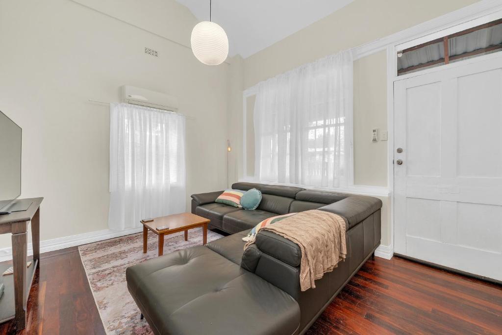 a living room with a couch and a table at Bassett Cottage in Gawler South with 3 bedrooms and close to city train and shops 
