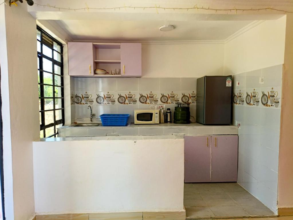 埃尔多雷特Camp Flo Eldoret -Homely Comfort in a Private Compound的厨房里有粉色和紫色的橱柜，还有一个微波炉