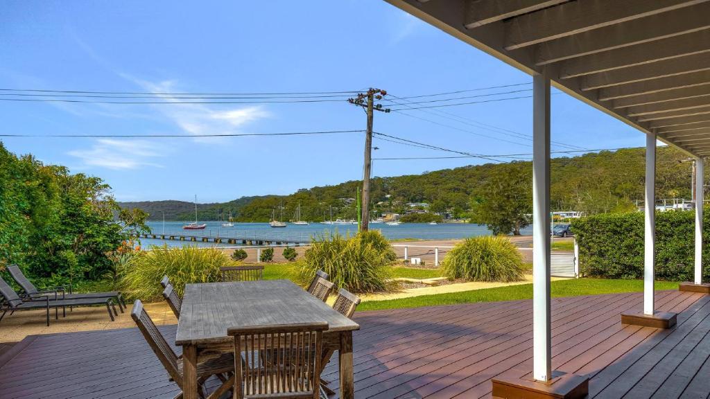 a table and chairs on a deck with a view of the water at 'Footsteps to the Bay' by HolidayCo in Pretty Beach