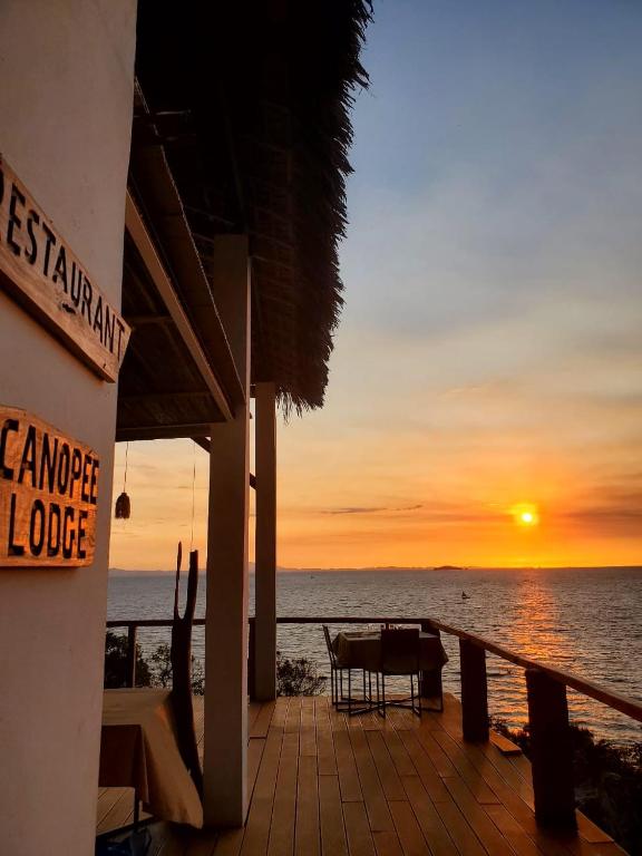 a sunset on the beach with a table and chairs at Canopee Lodge in Nosy Komba