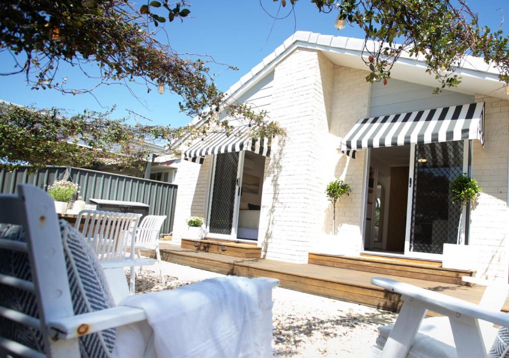 un patio con sedie bianche e una casa di Coastal Courtyard Retreat Jasmine Hideaway Sunshine Coast a Kawana Waters