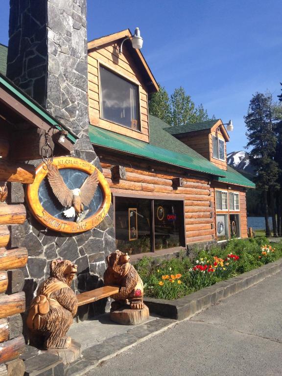 a log cabin with two bear statues in front of it at Summit Lake Lodge in Summit Lake