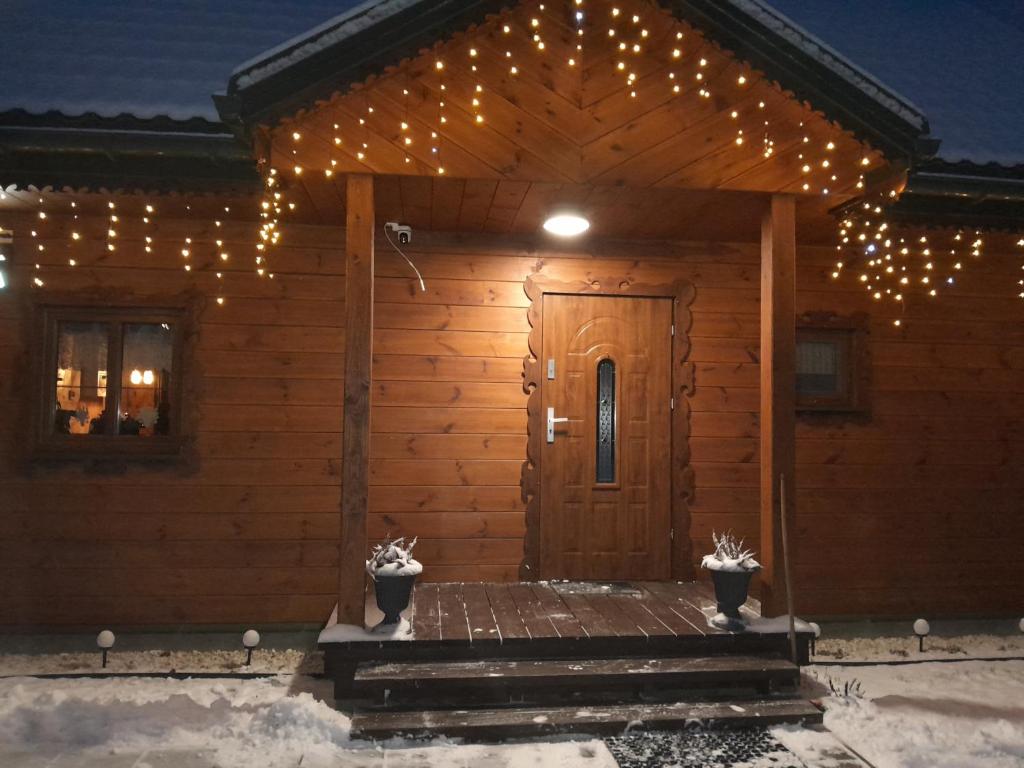 een houten hut met kerstverlichting bij Agroturystyka Przy Siole Budy in Białowieża