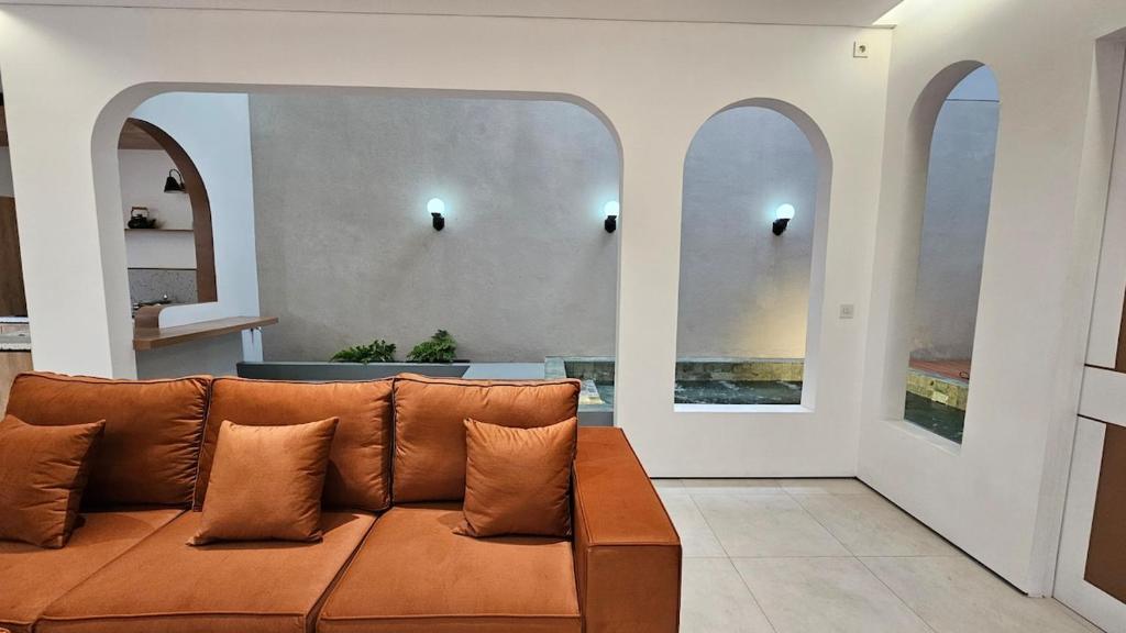 un canapé marron dans un salon avec des fenêtres dans l'établissement Villa Panda, Your Private Holiday Home in Malang!, à Sengkaling