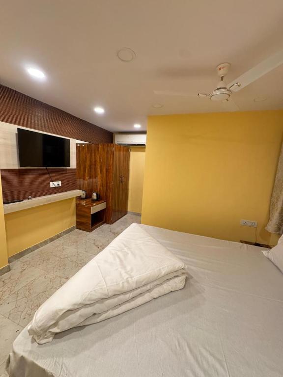 a bedroom with a white bed and a yellow wall at Velora Stays in Kolkata
