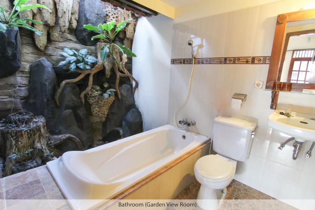 a bathroom with a bath tub and a toilet and a sink at Duta Guest House in Yogyakarta
