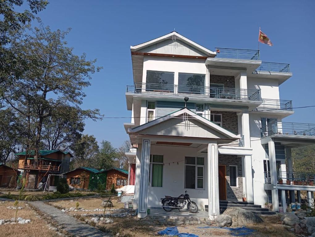 a white house with a bike parked in front of it at Star Amaya Homestay River Side Mountain and Forest View in Kangra Airport