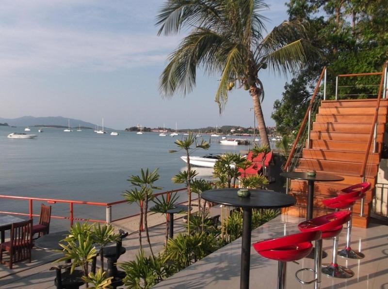 a patio with tables and chairs and a view of the water at Marina Residence in Bang Rak Beach