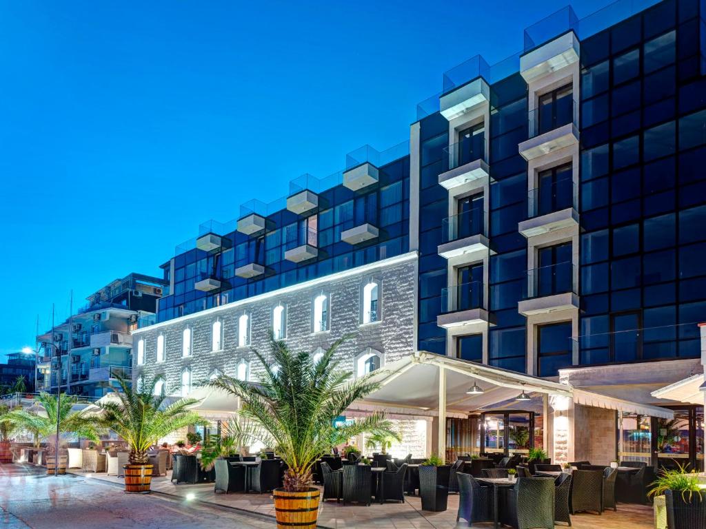 a hotel with tables and palm trees in front of a building at Hotel Antik in Balchik