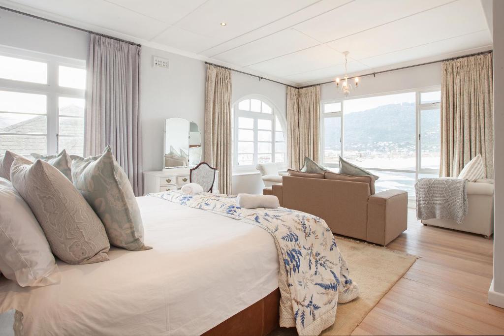 a white bedroom with a large bed and a living room at The Cove in Fish Hoek