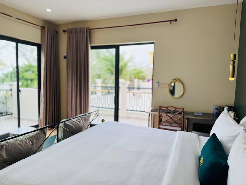 Schlafzimmer mit einem weißen Bett und einem Balkon in der Unterkunft Vrest Hotel Otres Beach in Sihanoukville