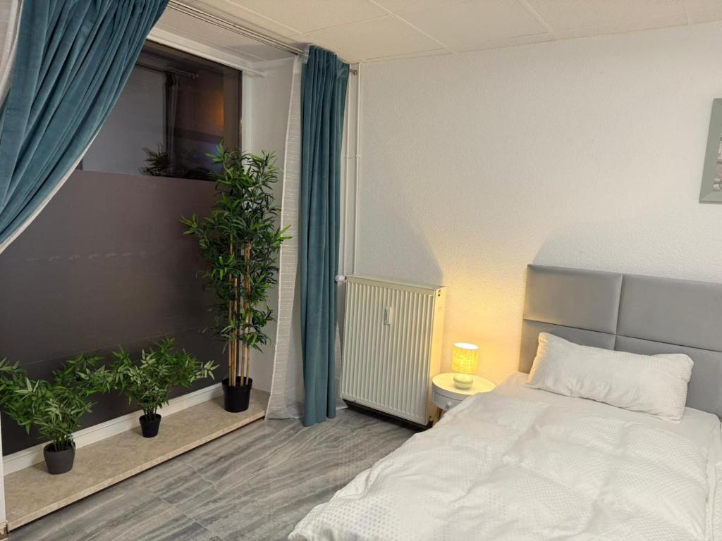 ein Schlafzimmer mit einem weißen Bett und Topfpflanzen in der Unterkunft Apartment Döbeln Centrum in Döbeln