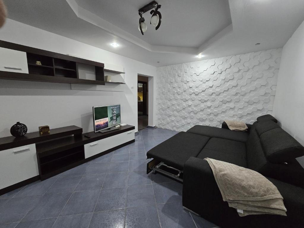 a living room with a black couch and a tv at AARON Apartament in Craiova