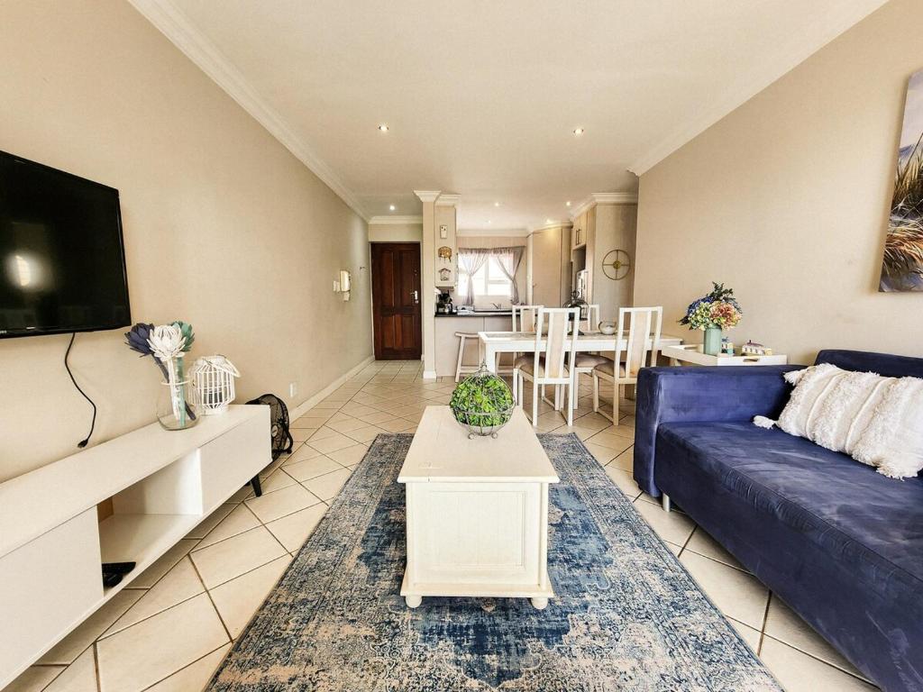 Una sala de estar con un sofá azul y una mesa. en Modern Coastal Apartment in J-Bay, en Jeffreys Bay