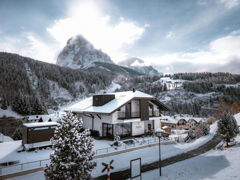ein Haus im Schnee mit einem Berg im Hintergrund in der Unterkunft Anna Lodges Dolomites in St. Christina in Gröden