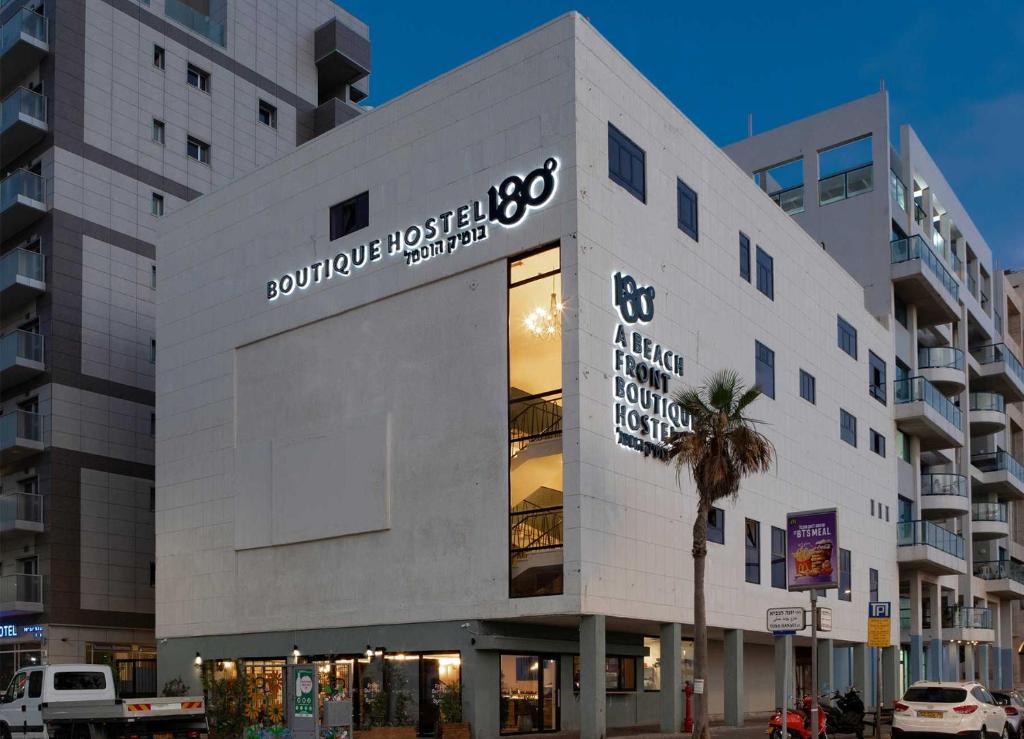a white building with a palm tree in front of it at 180 Boutique Hostel in Tel Aviv